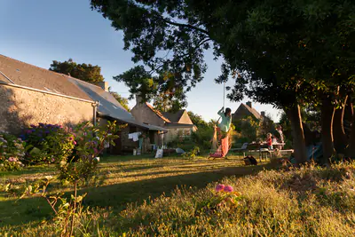R&uuml;ckseite des Hauses mit grossem Garten, B&auml;umen und einer Feuerstelle zum Grillen.