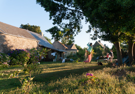 Rückseite des Hauses mit grossem Garten, Bäumen und eine Feuerstelle zum Grillen.